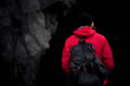 a person in a red jacket wearing a black summit expedition pack next to a cliff