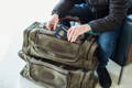 man sitting and putting his passport into the size pocket of a laurentian luggage bag